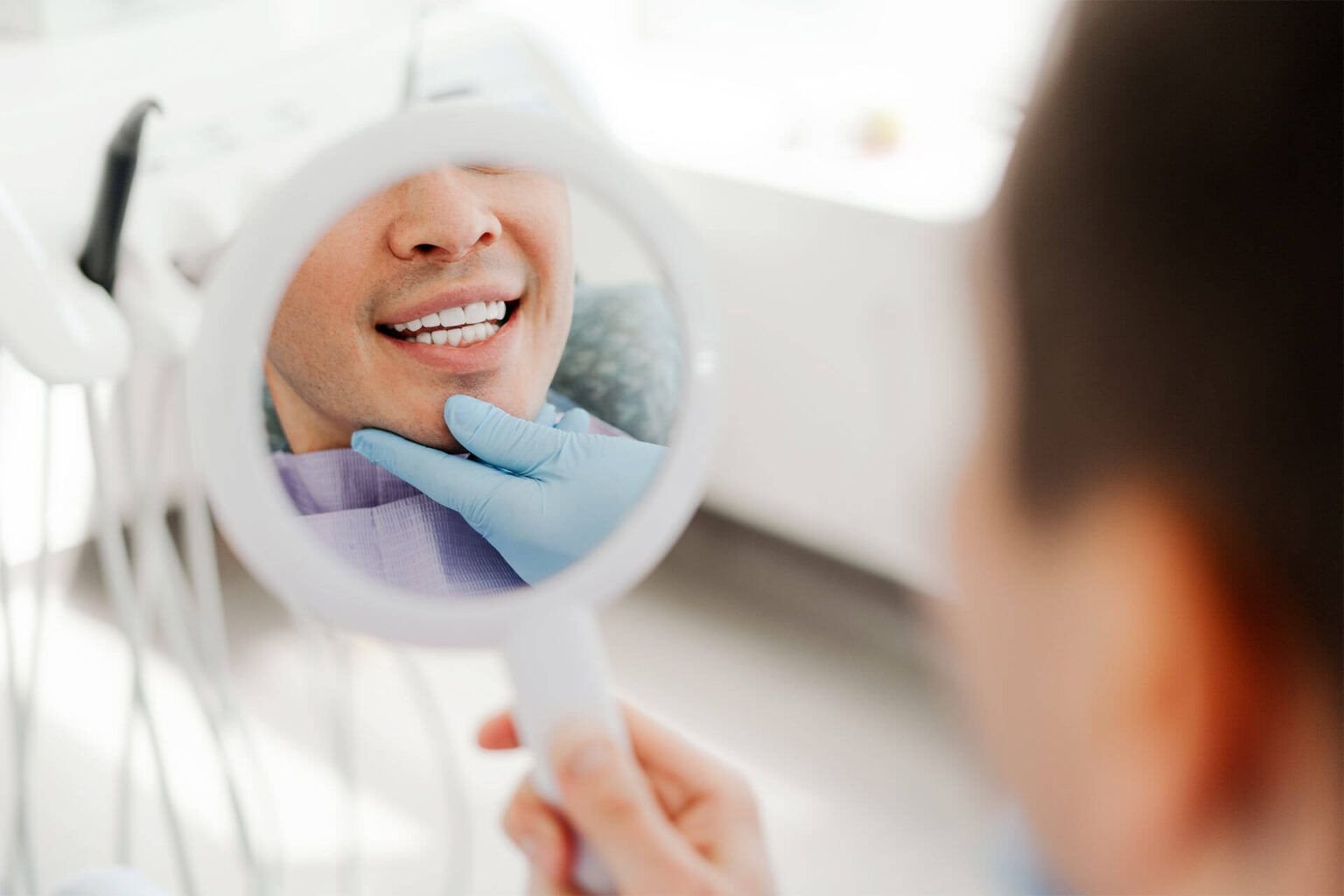 Smiling attractive young man, patient holding mirror